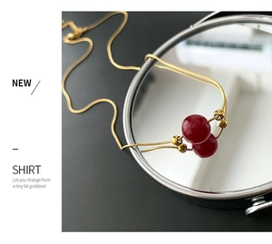 Close-up of titanium steel necklace with red beads on a golden snake chain and mirror reflections