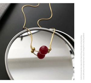 Macro detail of red bead pendant on golden snake chain necklace with mirror reflection