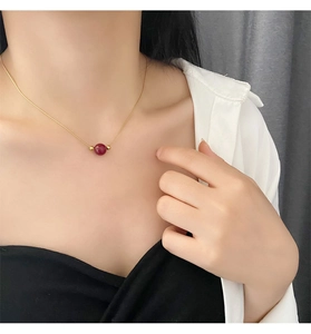 Detail of red bead titanium steel necklace on model, elegant gold snake bone chain style