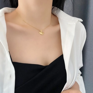 Golden ginkgo leaf pendant necklace in titanium steel on a model with white shirt