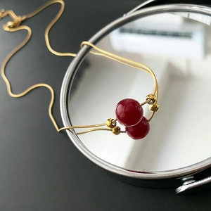 Minimalist titanium steel necklace with red beads and gold snake chain on mirror