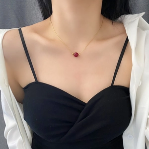 Minimalist gold titanium steel necklace with a red bead pendant worn on a model