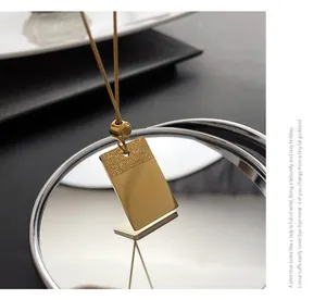 Dettaglio di una collana in acciaio al titanio dorato con ciondolo motivo nuvola di buon auspicio