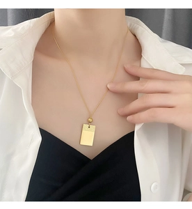 Dettaglio di una collana con pendente rettangolare dorato minimalista su catena fine