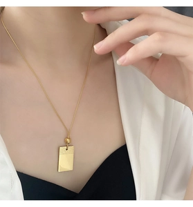 Dettaglio della collana con pendente geometrico in acciaio al titanio dorato sul modello
