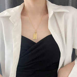 Collana in acciaio al titanio con pendente rettangolare dorato indossata da modella
