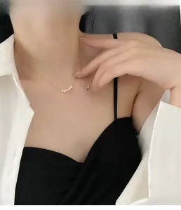 Detail shot of dainty gold titanium chain necklace featuring six lustrous white pearls