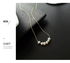 Detail of five glossy natural freshwater pearls on a gold titanium steel necklace chain