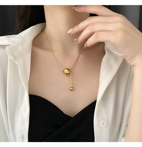 Gros plan sur un collier lariat doré minimaliste avec fermoir bille sur un mannequin