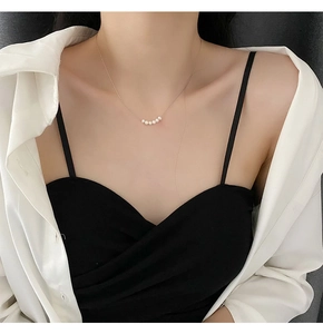 Detail of five freshwater pearls arranged on a delicate gold titanium steel necklace