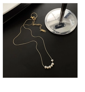 Macro view of gold stainless steel necklace with five freshwater pearls and S.STEEL tag