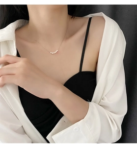 Close-up of minimalist titanium necklace with five small pearls on a golden chain