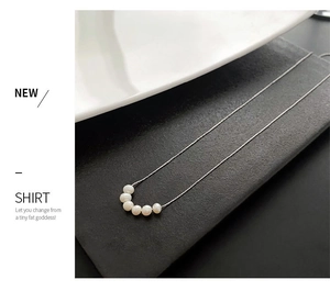 Detail of five white freshwater pearls on a delicate silver-colored titanium chain