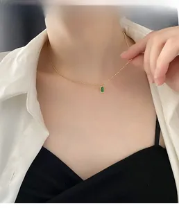 Primo piano della collana a sfere dorate con ciondolo a smeraldo rettangolare