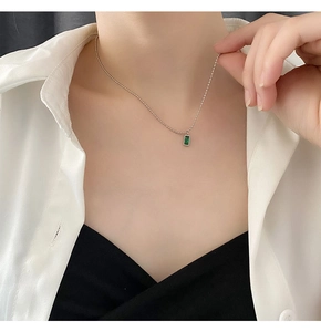 Primo piano della collana minimalista con catena a sfere d'argento e ciondolo verde smeraldo