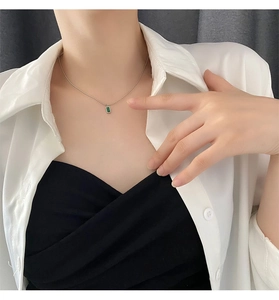Dettaglio della collana con smeraldo placcata oro 18k indossata con camicia bianca