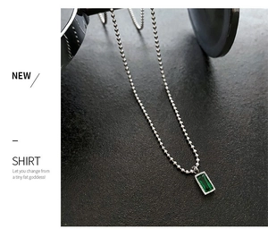 Dettaglio di un ciondolo rettangolare verde smeraldo su una collana a sfere d'argento