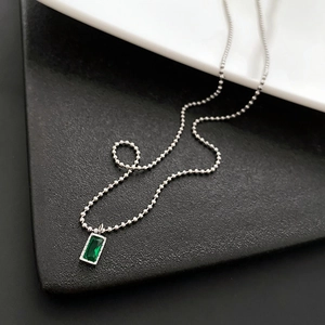 Elegante collana con pendente rettangolare verde smeraldo e catena a sfere argentata su nero