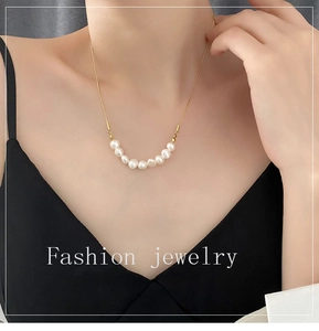 Gros plan d'un collier en chaîne dorée minimaliste orné d'une rangée de perles blanches