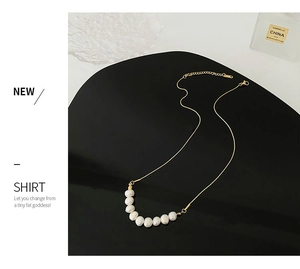 Gros plan sur un collier doré avec neuf perles baroques sur un support de présentation noir