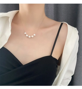 Gros plan d'un collier de perles souriant avec cinq perles lustrées sur une chaîne en titane