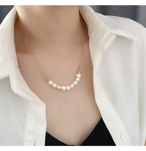 Gros plan d'une élégante chaîne en or avec perles blanches sur un mannequin minimaliste