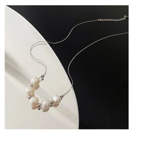 Gros plan détaillé de perles blanches et billes argentées sur un collier en titane