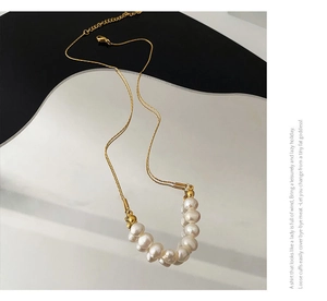 Détail macro du collier en titane doré avec perles baroques sur décor géométrique chic