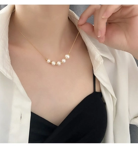 Gros plan d'un collier doré élégant avec cinq perles blanches sur une chaîne fine