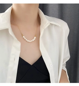 Détail d'un collier en or minimaliste avec sept perles brillantes porté au cou