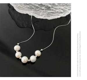 Détail du collier de perles élégant avec chaîne argentée sur support miroir noir de luxe