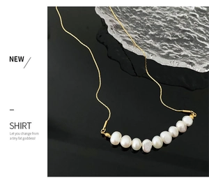 Détail d'un collier en or élégant avec dix perles blanches sur un fond noir texturé