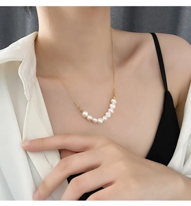 Gros plan détaillé d'un collier chaîne dorée avec sept perles blanches sur le cou d'un modèle