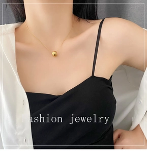 Close-up of a gold geometric rhombus pendant necklace worn by a model in a minimalist style