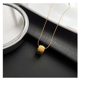 Macro shot of geometric diamond texture on gold-plated titanium transfer bead pendant