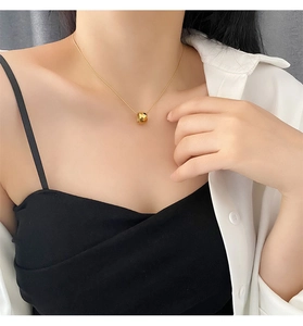 Close-up of a gold rhombus-faceted pendant necklace on a model for a chic minimalist look
