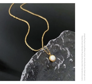 Macro view of vintage gold-plated necklace with round opal pendant on a textured stone