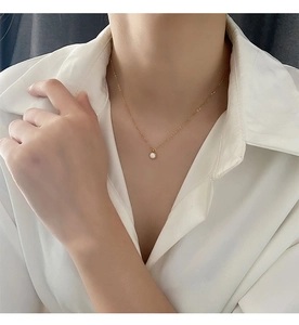 Close-up of a titanium steel gold necklace with a round shell pendant on a model