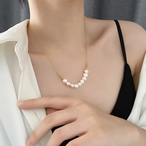 Collier minimaliste en acier titane avec neuf perles blanches sur chaîne dorée