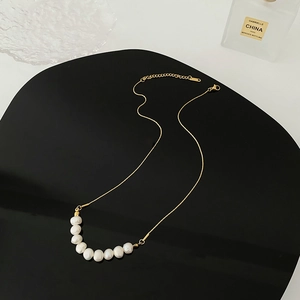 Collier en acier titane avec neuf perles blanches sur chaîne dorée au style minimaliste