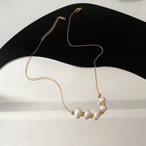 Collier élégant en acier titane doré avec perles blanches sur présentoir géométrique