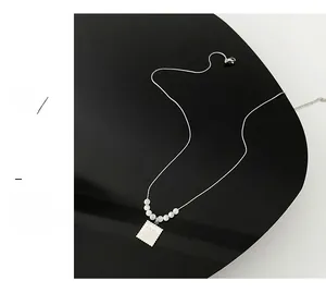 Detailed macro view of silver square Love Me pendant necklace with white pearl beads