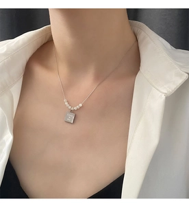 Detail of square shell pendant necklace with Love Me engraving and small white beads