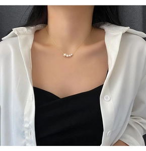 Detail of elegant gold chain necklace featuring four natural white pearls on a model