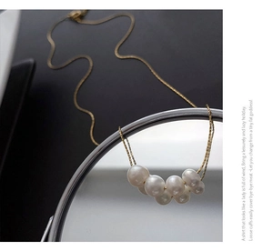 Detailed close-up of natural white pearls arranged on a fine gold titanium steel chain
