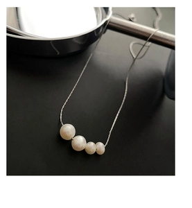 Detail of four natural white pearls on a slim silver titanium steel necklace chain