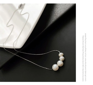 Close-up of graduated natural white pearls on a slim titanium steel necklace chain