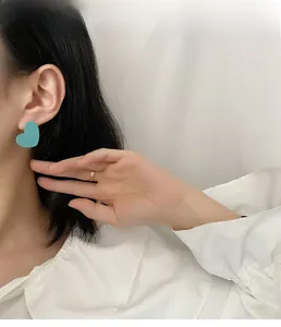 Close-up of a matte sky blue heart-shaped earring worn by a model for a chic look