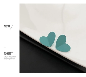 Detailed close-up of matte teal heart stud earrings with minimalist 3D folded metal design