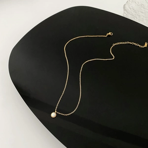 Elegant gold titanium steel necklace with a round white pendant and vintage grain edges